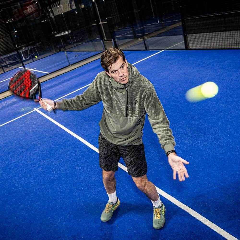 Padelspeler slaat de bal op een blauwe padelbaan