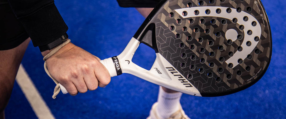 Hand om het handvat van een padelracket met een witte grip